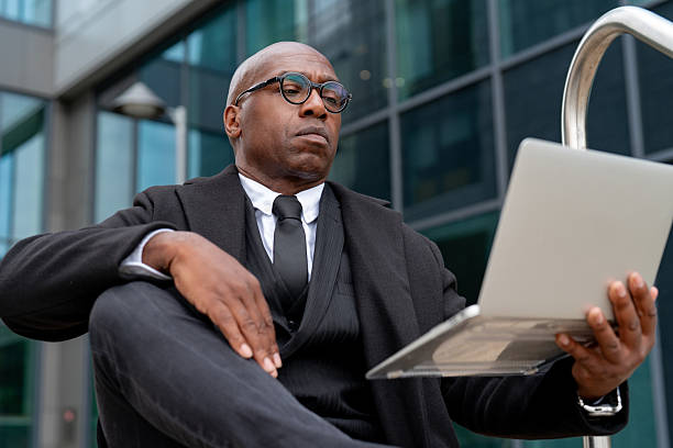 istock Businessman working on laptop outside modern office building in urban setting during daytime 2248685568