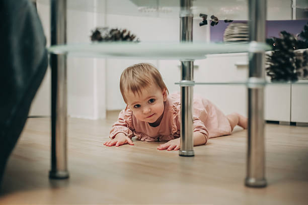 Little boy looking for a crayon under the sofa. He looks curious and playful.