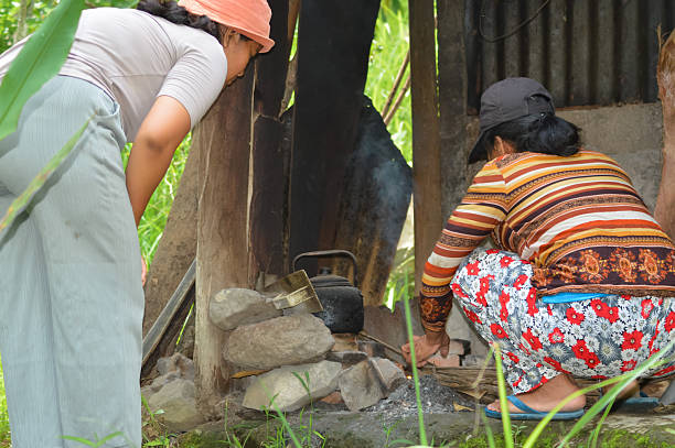 Two Women Starting a Fire on a Stone Stove in a Rustic Field Hut