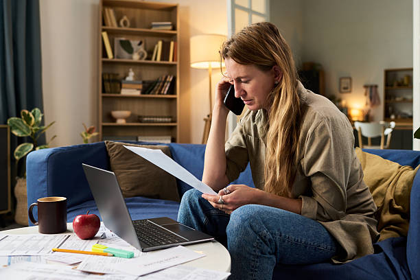 istock Caucasian Young Woman Reviewing Tax Documents While Talking on Smartphone 2248689954