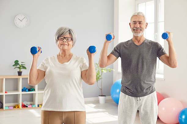 istock Happy Elderly Couple Exercising With Dumbbells In Gym 2248690708