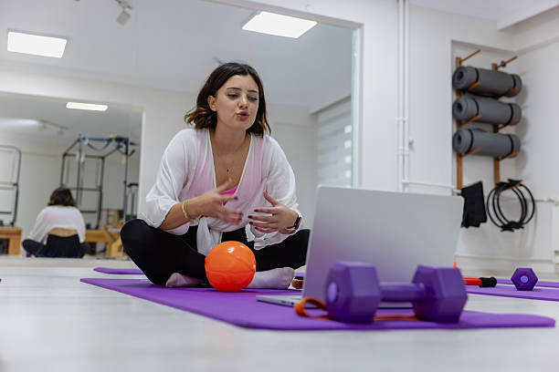 Young Pilates Instructor Gives Online Exercise Classes with a Ball in the Studio