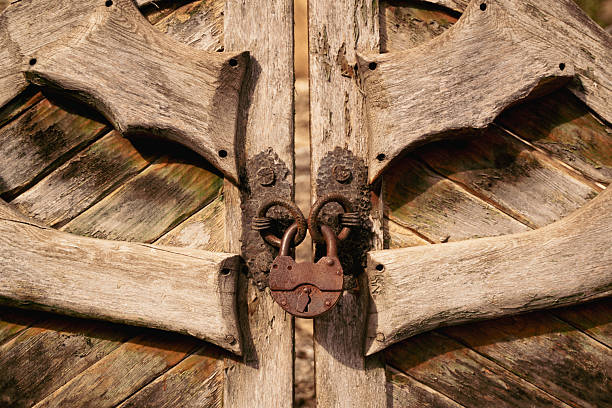 Rustic wooden gate with weathered texture and antique iron lock, symbolizing security and tradition in rural setting, front view in daylight
