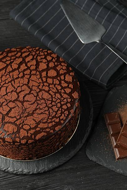 istock Delicious truffle cake, server and chocolate pieces on black wooden table 2248692164