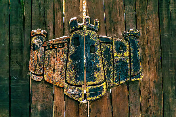 A weathered wooden fence with a large rusted metal sculpture of a dragon or similar creature