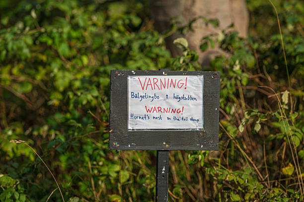 Warning sign about hornets nest written in two languages.