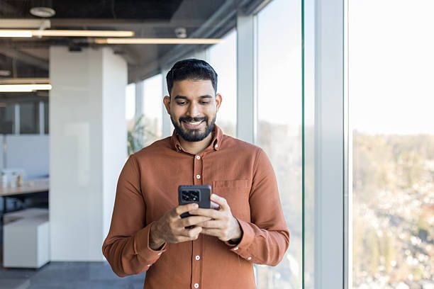 istock Indian businessman using phone smiling in modern office 2248694730