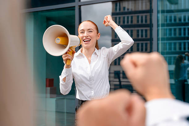 istock Confident woman leading a rally with a megaphone in a modern urban setting during daylight hours 2248695390