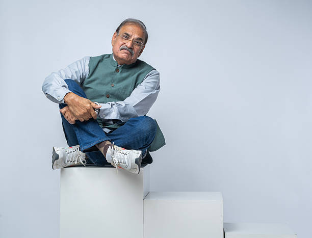 Full length of senior politician laughing while sitting with legs crossed on block against white background