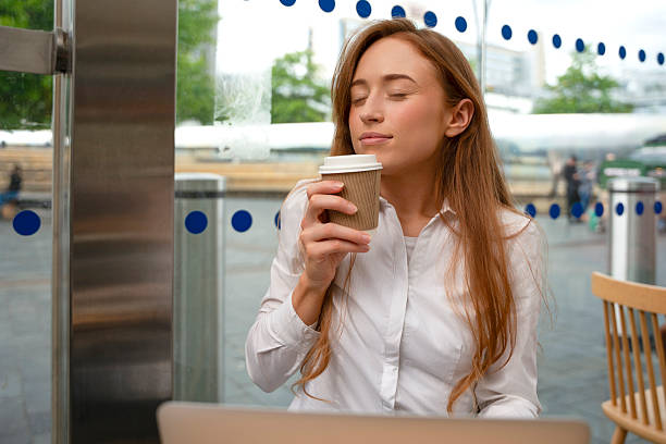 Young woman enjoying coffee while working at a cafe with a relaxed atmosphere and modern design