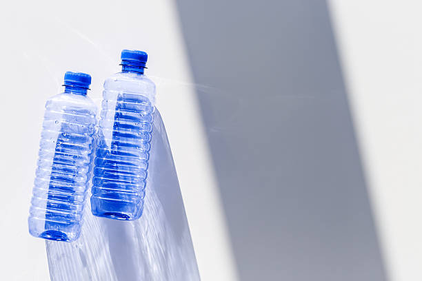 istock Transparent plastic bottles with blue caps and sun shadows on light background. Top view Water bottles at natural light. Themes of recycling, sustainability, water conservation, minimal style 2248697742