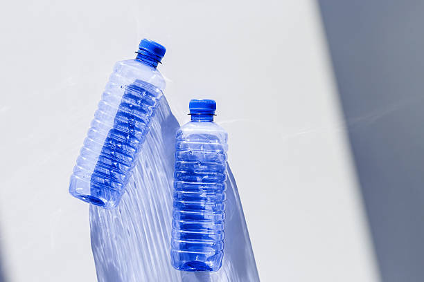 istock Blue plastic water bottles on white blue background with sunlight shadow and sun flare, Minimal top view photo, themes of ecology, recycling, sustainable living, reduce disposable plastics 2248697748