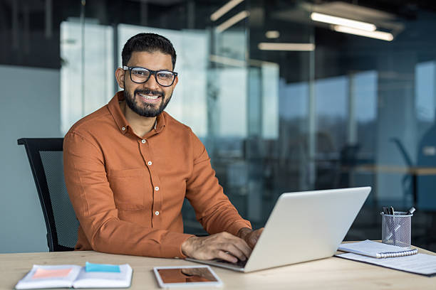 istock Indian businessman smiling while working on laptop in modern office 2248698247