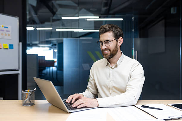 istock Smiling young man working in the office on a laptop 2248698762