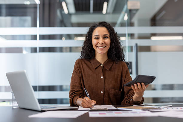 istock Young businesswoman smiling while calculating finances and working in office 2248699996