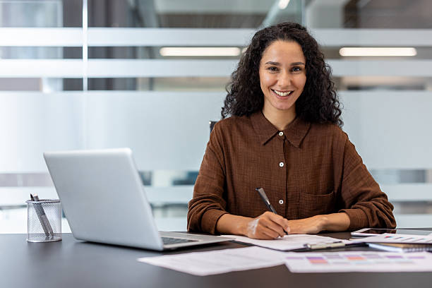 istock Professional businesswoman smiling, writing notes at office desk 2248701811