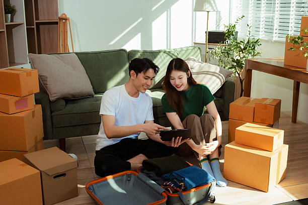 istock Young couple relaxing sitting on the sofa using the computer laptop around cardboard boxes, very happy moving to a new house. 2248704799