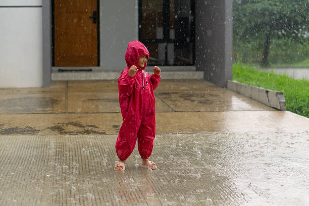 Daughter playing on rainy days wearing red rain coat