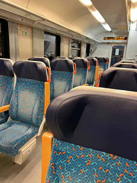 istock Empty suburban train carriage with blue patterned seats and orange handles, shallow depth of field, evening commute scene. 2248707379