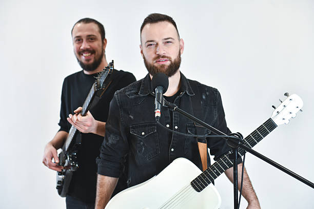 istock Energetic Two-Musician Band With Guitars Performing in Studio Against White Background, Mid-Performance, Live 2248712685