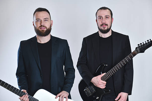 istock Two Man Band Posing With Guitars In Black Suits Against White Studio Background 2248714432