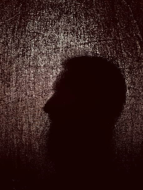 Silhouette of a person behind a dark fabric, mysterious and suggestive atmosphere, thanks to the strong backlighting that emphasizes the silhouette and the irregular texture of the fabric that creates a dramatic and almost theatrical visual effect.