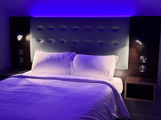 Illuminated lamp and bed in dimly lit bedroom at night
