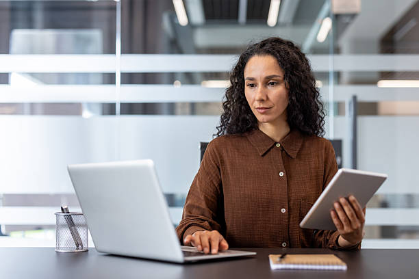 istock Businesswoman multitasking using laptop and tablet in office 2248715236