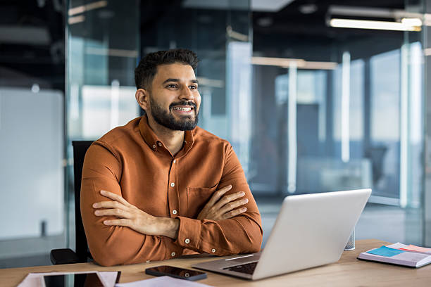 istock Confident indian businessman smiling sitting at office desk 2248716239