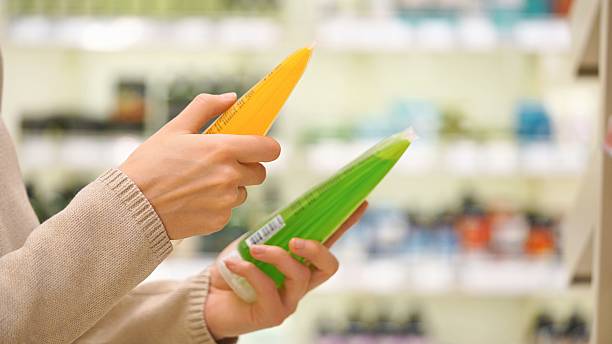 Woman comparing body wash and shower gel in a store aisle