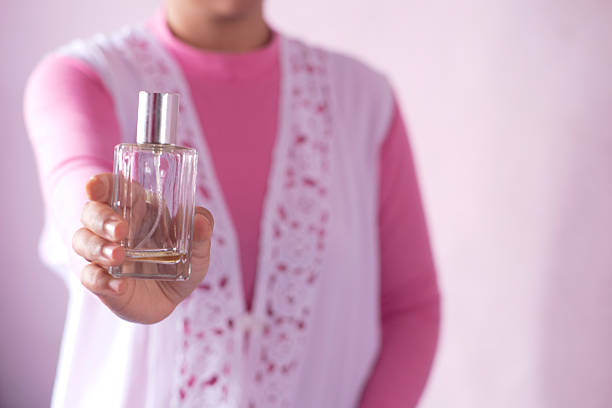 women with elegnt pink oufilt showing s glass bottle perfume