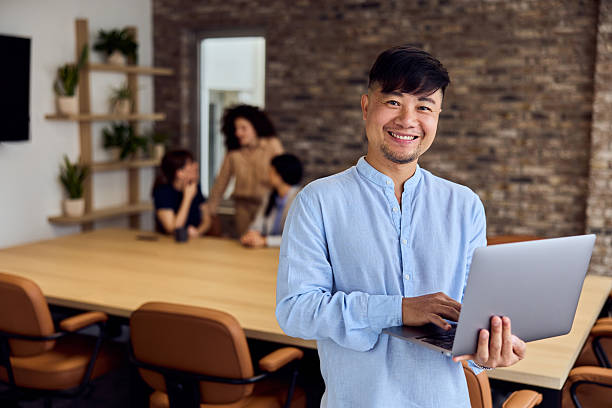 istock Asian Professional With Laptop In Modern Office During Team Meeting In Open Workspace 2248720313