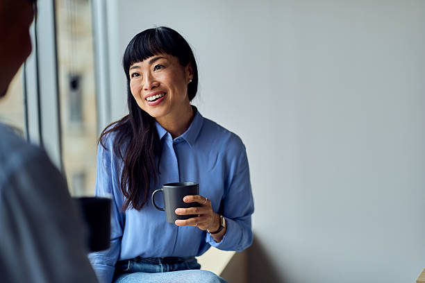 istock Asian Woman Smiling While Holding A Mug In A Modern Office Workspace During Coffee Break 2248720318