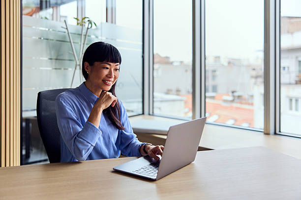 istock Asian Woman Working At Modern Office Desk With Laptop In Bright Workspace 2248720329