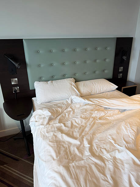 istock Image of bedroom with messy white bedsheets on double bed / leather studded headboard, relaxed sleep space, cozy interior, residential design 2248720914