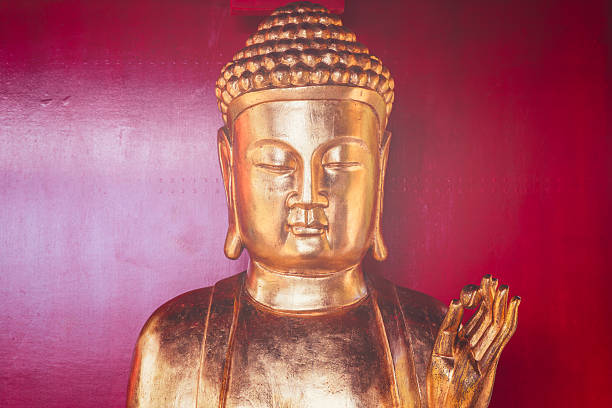 istock Golden Buddha statue with soft light glowing on red background and peaceful expression 2248720983