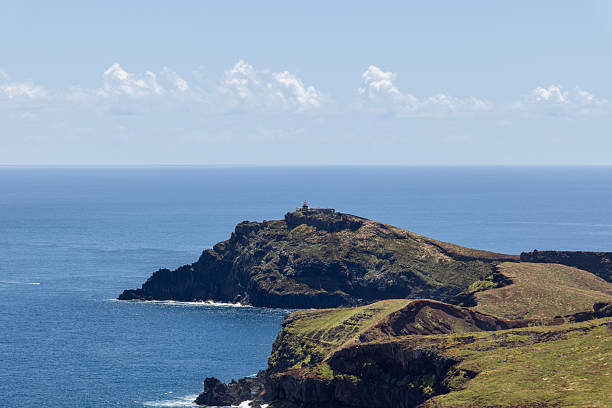 istock Lighthouse at Sao Lourenco tip with rugged cliffs calm sea and clouds on clear horizon line. Madeira 2248721645