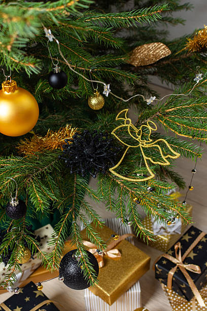 istock A festive scene featuring gold and black gift boxes, surrounded by shimmering candlelight and stylish decorations under a beautifully decorated Christmas tree, exuding elegance and charm 2248722547