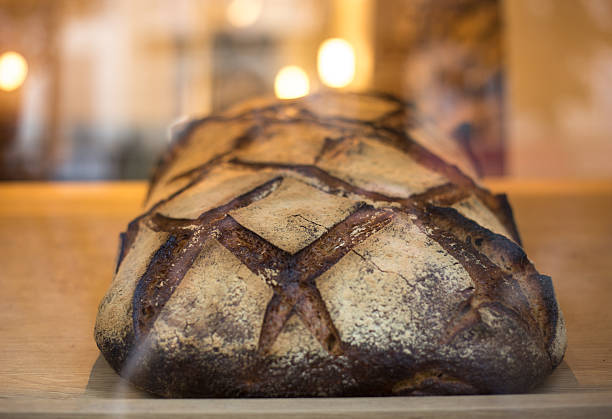 Sliced Italian Batard bread that looks like an Easter bunny on a round wooden cutting board on a wooden table background.