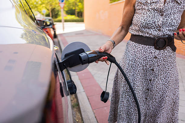 istock Woman plugging charging cable into electric vehicle 2248725139