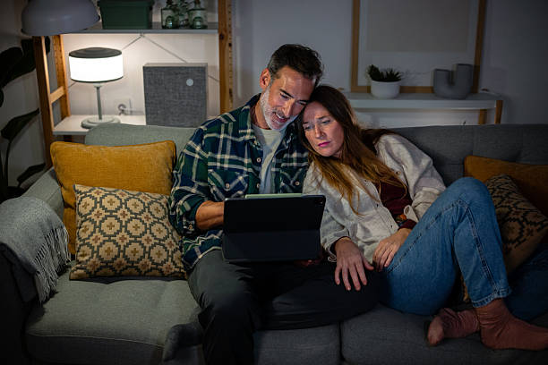 istock Couple relaxing on sofa watching tablet at home 2248726172