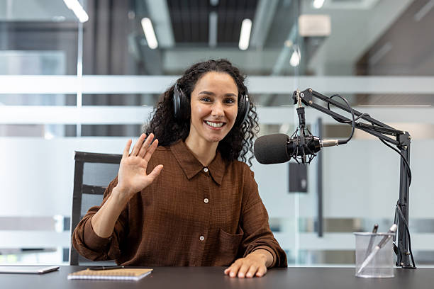 istock Woman podcast host recording with microphone waving hand 2248732563
