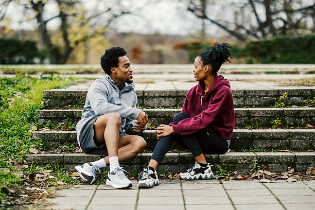 istock Black couple sitting on stairs talking in park 2248733581