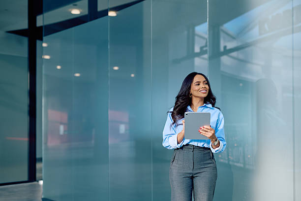 istock Businesswoman standing in modern office holding digital tablet looking at copy space thinking about future success 2248734461