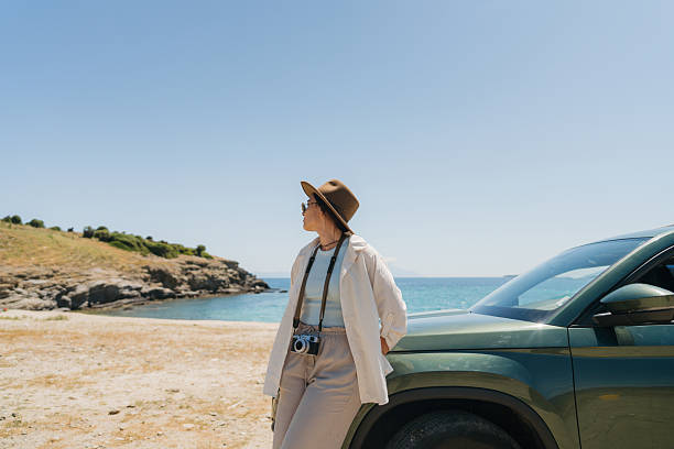 Photo of a female photographer on a new assignment, explores the beautiful seashore by car