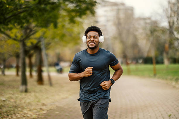 istock Smiling man running in park wearing headphones 2248736343