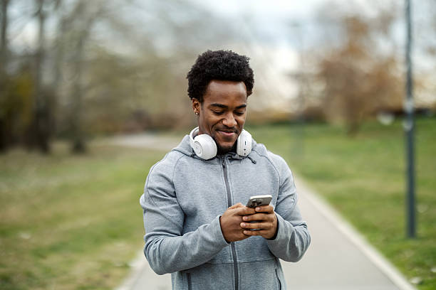 istock Young man using phone and headphones in park 2248736384