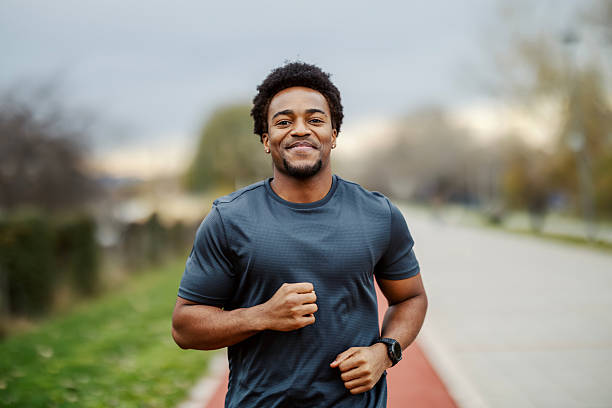 istock Black man smiling running on park track 2248736393