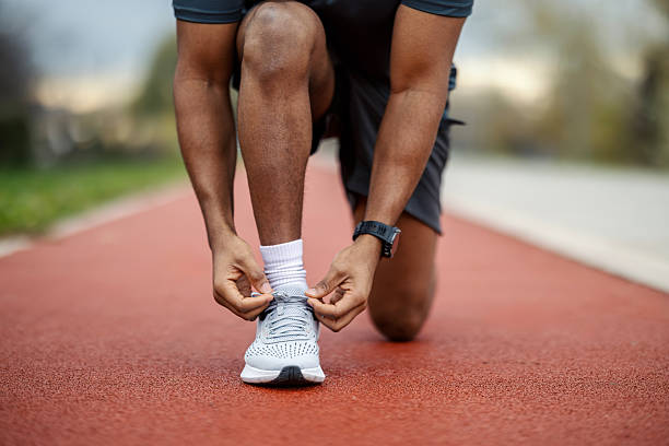 istock Black man tying shoe laces on running track 2248736415