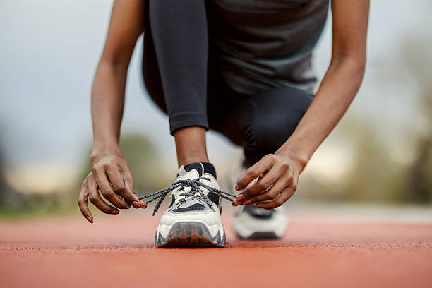 istock Black woman tying running shoe on track preparing for workout 2248736417